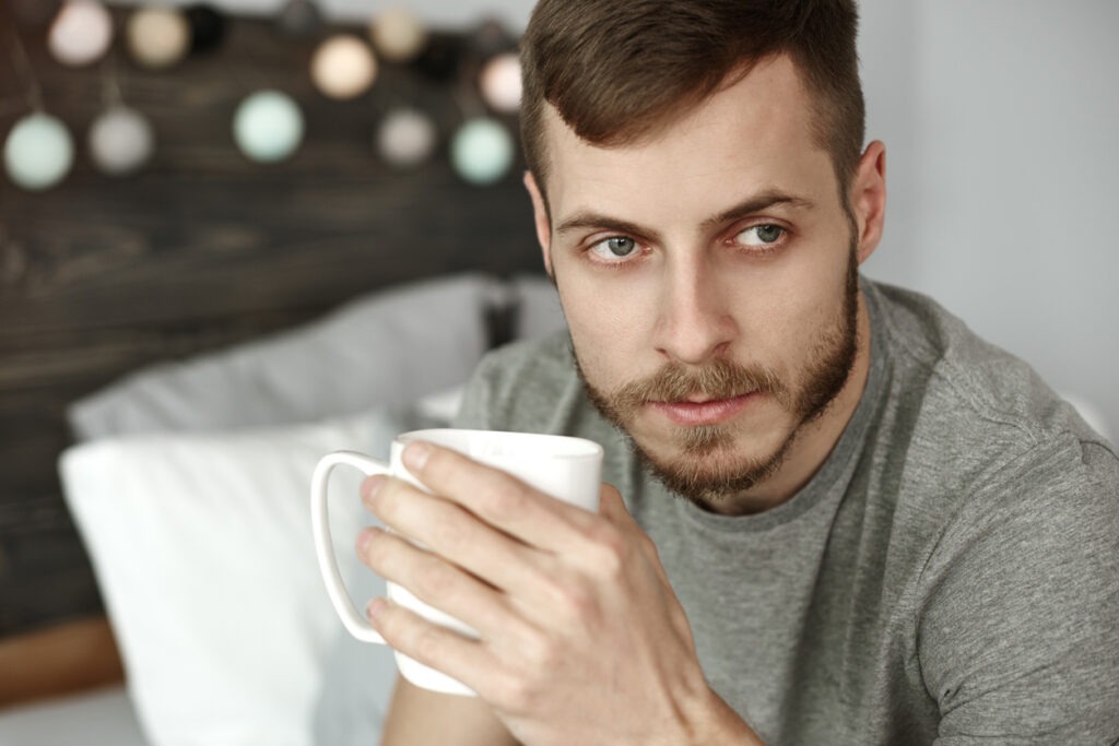 A man looking thoughtful drinking his morning coffee.
